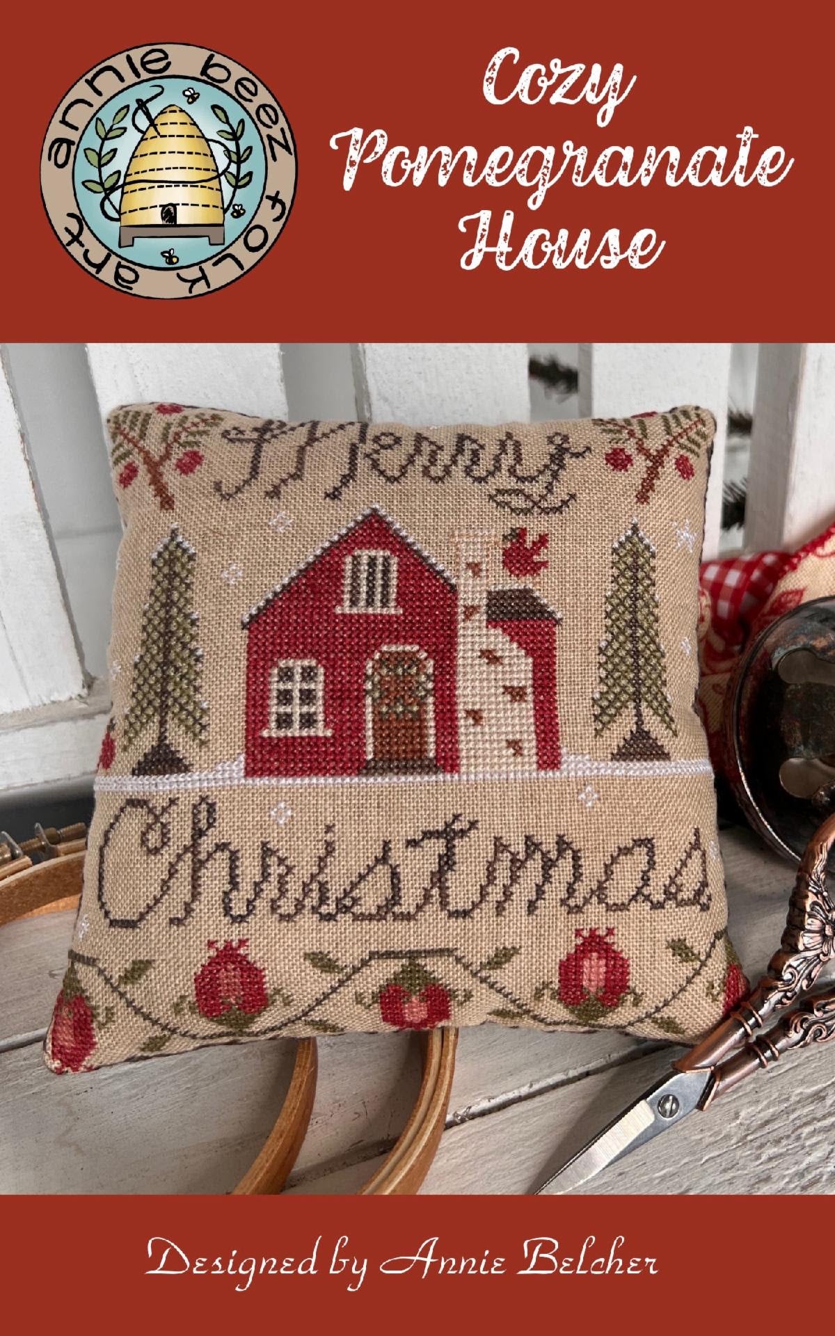 Cozy Pomegranate House by Annie Beez Folk Art: pillow with a red cottage, trees, pomegranate border, and Merry Christmas lettering.