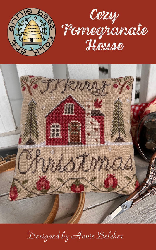 Cozy Pomegranate House by Annie Beez Folk Art: pillow with a red cottage, trees, pomegranate border, and Merry Christmas lettering.